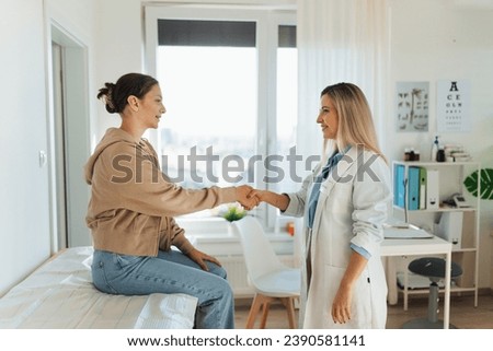 Teenage patient arriving at appointment with doctor, shaking hands with female pediatrician, physician. Teen girl have consultation, first visit with gynecologist. Concept of preventive health care Royalty-Free Stock Photo #2390581141