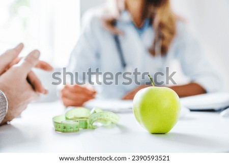 Healthy food concept. Cropped close up of woman doctor dietician recommending senior male patient fresh apple. Weight loss, diet for burning calories. Eating disorder issues Royalty-Free Stock Photo #2390593521
