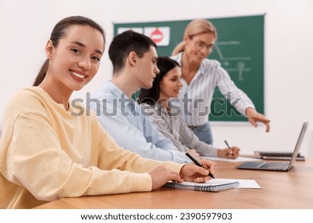 Happy woman making notes at desk in class during lesson in driving school