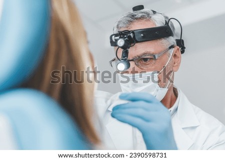 Close up of senior doctor otolaryngologist examines adult woman for sore throat. Medical health checkup. Vocal cords illnesses prevention treatment Royalty-Free Stock Photo #2390598731