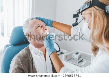 Doctor checking man throat with medical stick. Vocal cords medical health checkup in clinic. Glands swollen. Otorhinolaryngologist visit Royalty-Free Stock Photo #2390598741