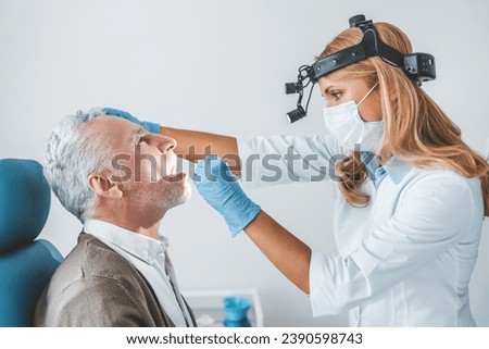 Doctor examines senior man for sore throat. Flu coronavirus influenza treatment prevention. Vocal cords medical health checkup in clinic. Glands swollen Royalty-Free Stock Photo #2390598743