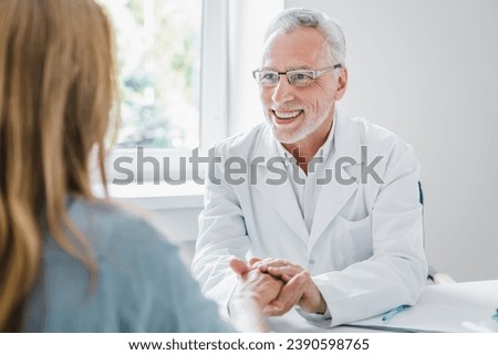 Senior doctor supporting woman patient and holding her hands while appointment in clinic. Trusting medical worker. Helping hand to patient with cancer, diagnosis, illness Royalty-Free Stock Photo #2390598765