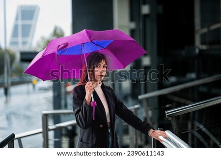 Caucasian girl, brown hair, chic, rainy Madrid, glass buildings, umbrella, stylish.