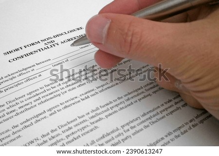 Close-up on a the hand of a man feeling a "Short form non-disclosure and confidentiality agreement". Royalty-Free Stock Photo #2390613247