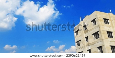 A tall building with a blue sky and white clouds in the background