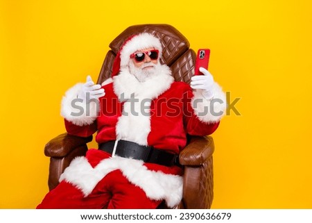 Photo of grandfather santa sit leather chair hold smart phone make selfie video call christmas greeting isolated on yellow color background