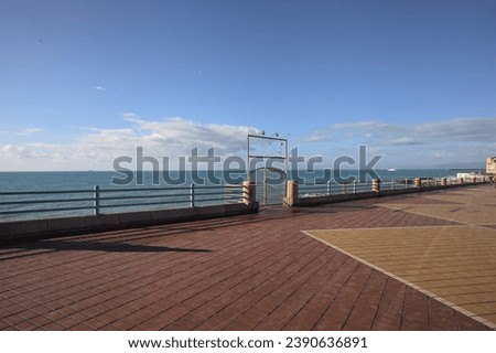 Entrance  gate in a railing on a promenade by the sea on a sunny day Royalty-Free Stock Photo #2390636891