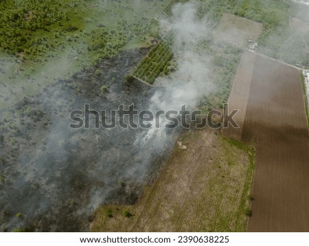 Aerial view of agricultural waste bonfires from dry grass and straw stubble burning with thick smoke polluting air during dry season on farmlands causing global warming.