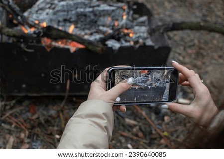 Woman taking picture of a fire in grill on a smartphone