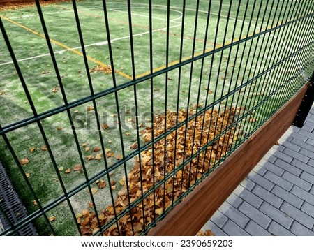 multifunctional outdoor playground in the school yard. green artificial lawn made of plastic carpet. basketball hoops and soccer goals. around the high net and railing. leaf cleaning, bench