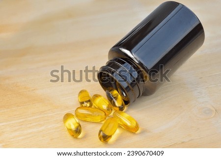 Cod liver oil capsules on wooden background.