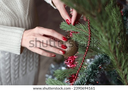 Female hands with red manicure and gold foil on the nails. Winter and Christmas time concept. Manicured woman's hands with Christmas decoration.