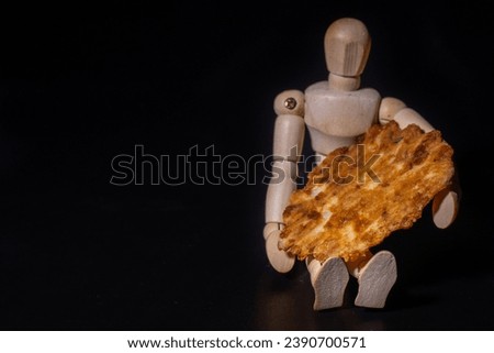 Dark background with a silhouette of a wooden man holding cheese waffles baked in the kitchen. Soft selective focus. Artificially created grain for the picture