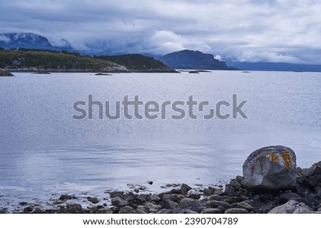 Landscape picture of the dramatic scandinavian coast of norwegian sea on the island Otroya in the middle of Norway. Picture is taken during beautiful summer calm and cloudy sunset in the blue hour.