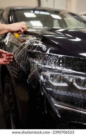 Protection of hood and front of the car with a colorless protective film. Royalty-Free Stock Photo #2390706523