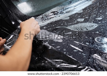 Protection of hood and front of the car with a colorless protective film. Royalty-Free Stock Photo #2390706613