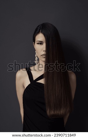 A sophisticated portrait of a woman in a black dress, her long straight hair and intense gaze exuding elegance and modernity Royalty-Free Stock Photo #2390711849
