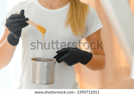 Portrait of a female caucasian beautician holding a jar of sugar paste for sugaring.