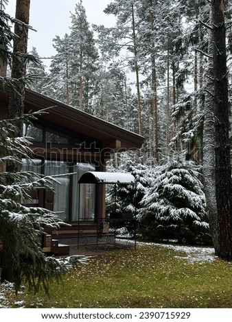 Magical atmospheric winter picture. Stylish modern wooden house at the field among the snowy woods. Christmas mood