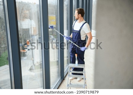 Male worker washing window glass.