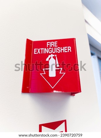 fire extinguisher and sign against white wall, safety concept in home or workplace