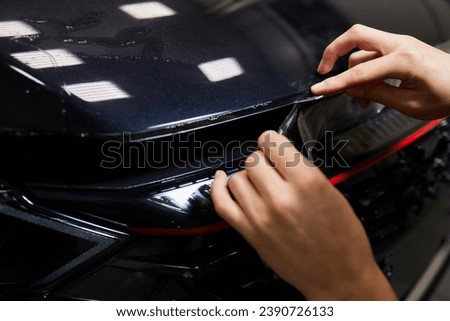 Protection of hood and front of the car with a colorless protective film. Royalty-Free Stock Photo #2390726133