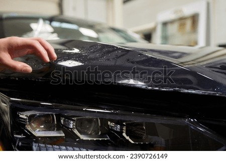 Protection of hood and front of the car with a colorless protective film. Royalty-Free Stock Photo #2390726149