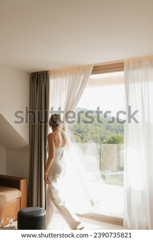 Woman opening curtains in a luxury hotel suite overlooking the mountains