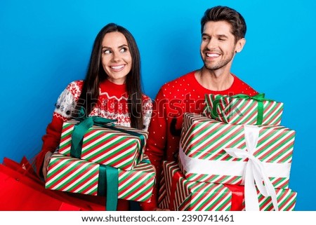 Photo portrait of lovely young spouses hold presents pile wondered wear x-mas ornament red sweaters isolated on blue color background