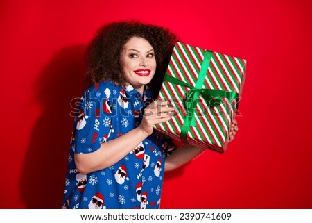 Photo portrait of pretty young girl hold big giftbox receive present wear trendy blue print x-mas outfit isolated on red color background