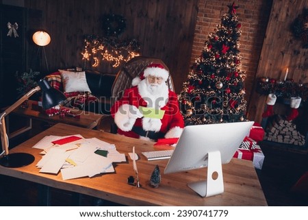 Photo of good mood funky santa claus wear red costume reading christmas greetings postcards indoors north pole office