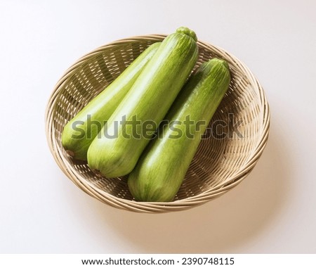 Close up of three stacked raw young pumpkins on bamboo basket and white floor, South Korea
