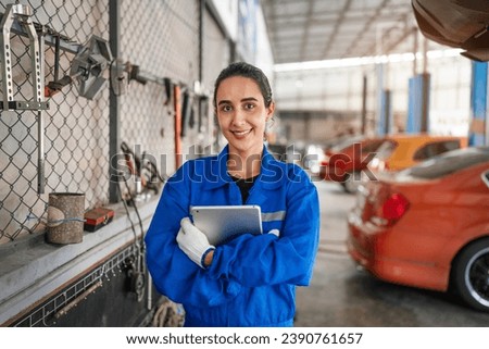 Portrait of woman auto mechanic working at car repair shop with looking at camera.
