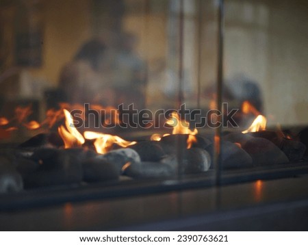 Modern gas fireplace with dancing flames over pebbles, reflecting a cozy indoor atmosphere. Royalty-Free Stock Photo #2390763621