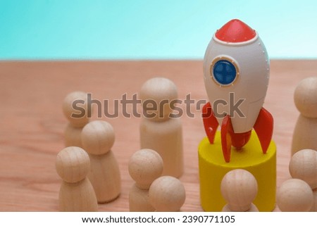 The wooden figures standing together, encircling a rocket emblem, showcased the teamwork and strategic vision driving the company's journey to reach the pinnacle of global business success Royalty-Free Stock Photo #2390771105