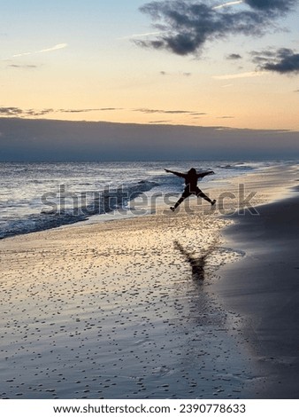 Boy running down the beach at sunset