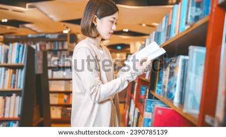 Portrait of young adult southeast asian woman reading book at bookstore shop. University student female leisure on weekend. Relax trend with knowledge.  Royalty-Free Stock Photo #2390785139