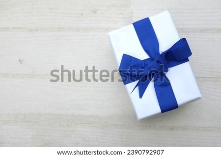 a bird's eye view of photo of  gift box  white with blue ribbon bow isolated on a white on the wooden table with empty space