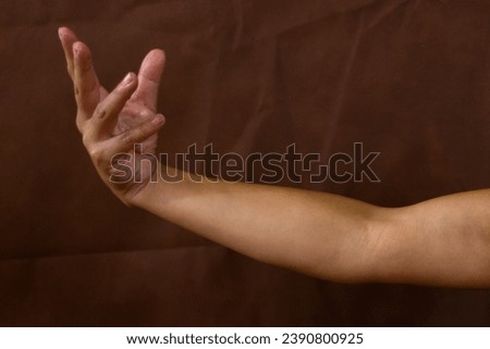 Arm with power hands, view from above on brown background