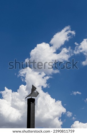 Black fireplace chimney isolated against a white cloud in a blue sky