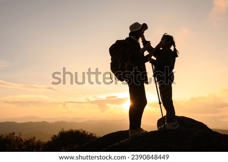 Traveling mother and son family enjoying the view on the mountain side at sunset silhouette