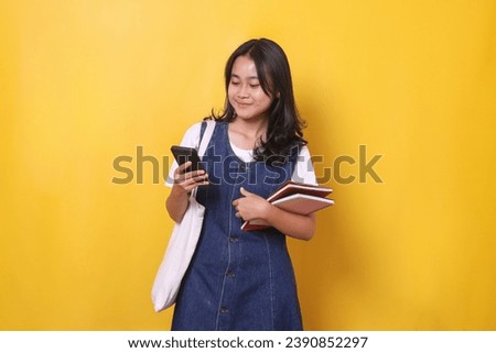 Smiling young Asian student girl using mobile phone