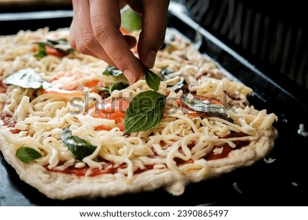 making homemade pizza with dough tomatoes sweet basil with hand