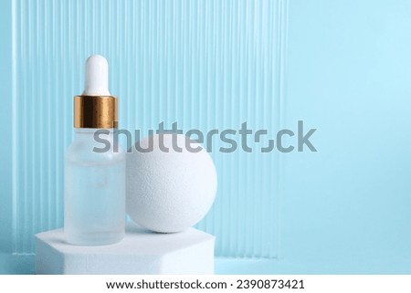 Stylish presentation of cosmetic serum on light blue background, space for text