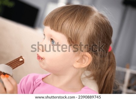 Little girl eating sweet chocolate candy with trace at her mouth portrait