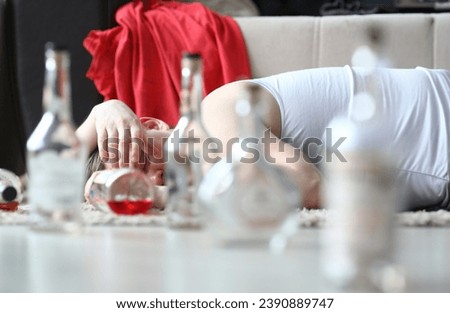 Drunken man lying among pile of empty bottles in dirty apartment concept Royalty-Free Stock Photo #2390889747