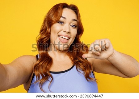 Close up young chubby overweight plus size fat fit woman wears blue top warm up train do selfie shot pov on mobile cell phone isolated on plain yellow background studio home gym. Workout sport concept