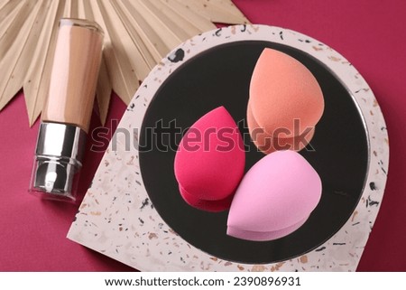 Stylish presentation of makeup sponges and skin foundation on pink background, above view