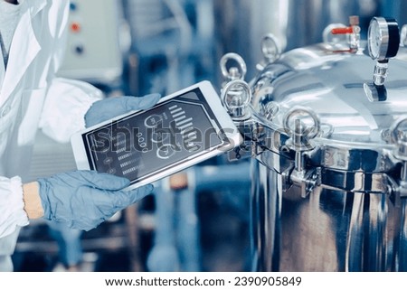 closeup engineer worker tablet in food and drinks factory industry monitor operate control inspecting production line high pressure tank production line. Royalty-Free Stock Photo #2390905849